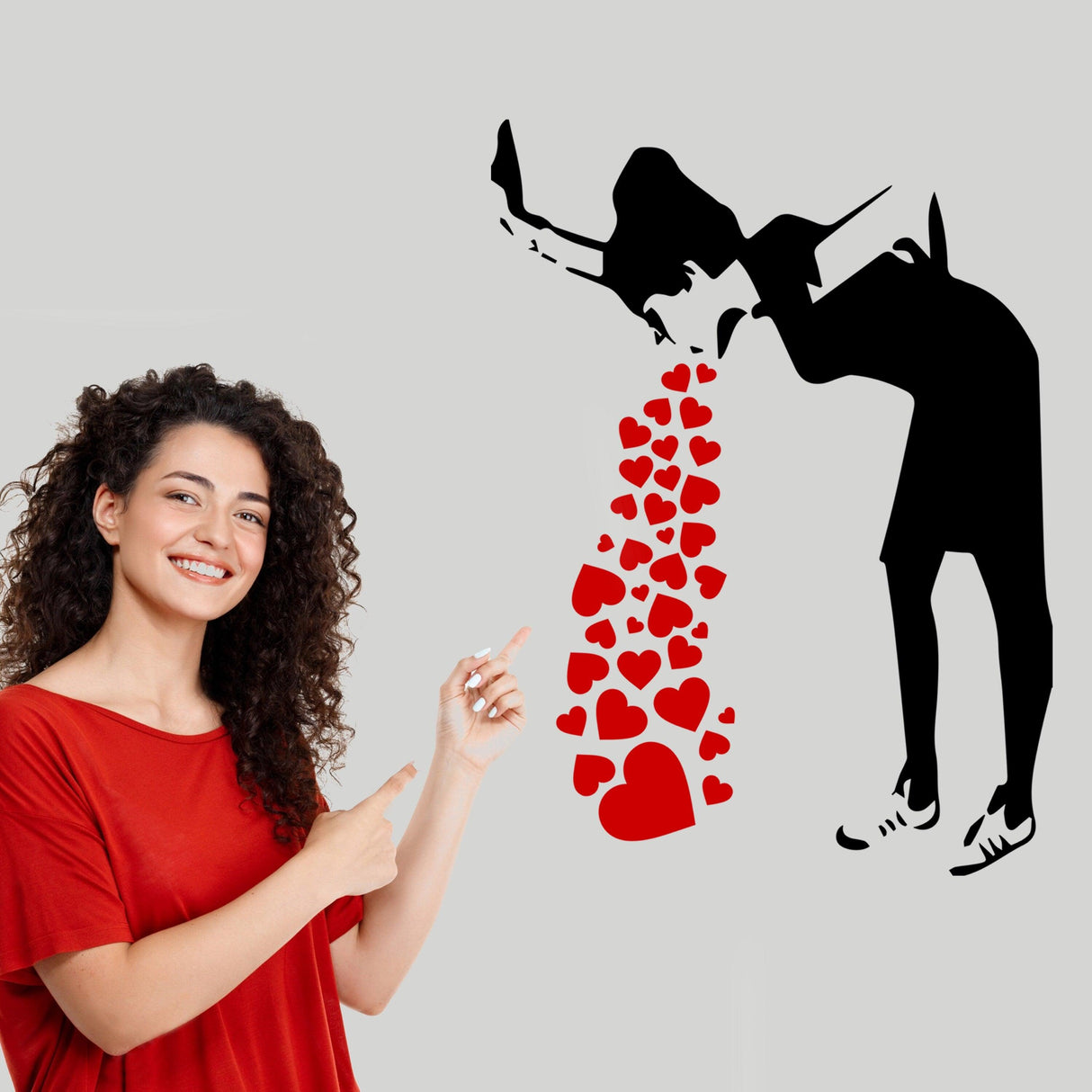 Woman pointing at Banksy-inspired Love Sick Girl wall decal with hearts, urban vinyl sticker for stylish decor.