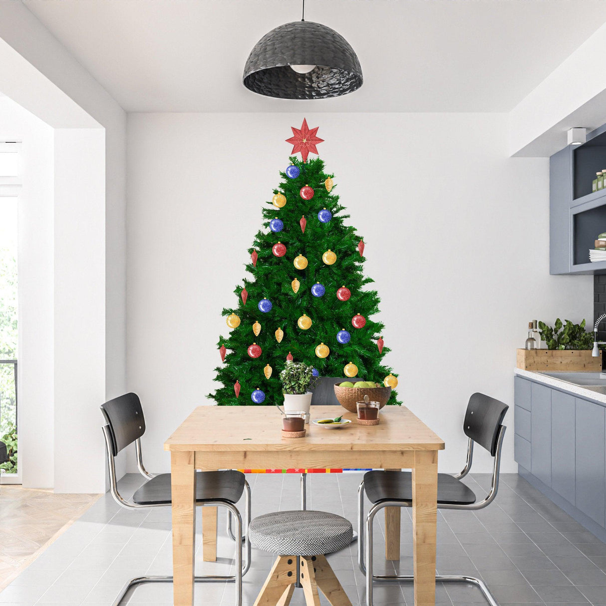 Decorated Christmas tree with colorful ornaments in a modern kitchen, creating a festive holiday atmosphere.