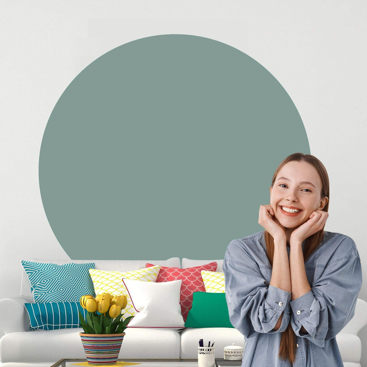 Smiling woman in modern living room with Circle Boho Wall Decal and colorful throw pillows on sofa.