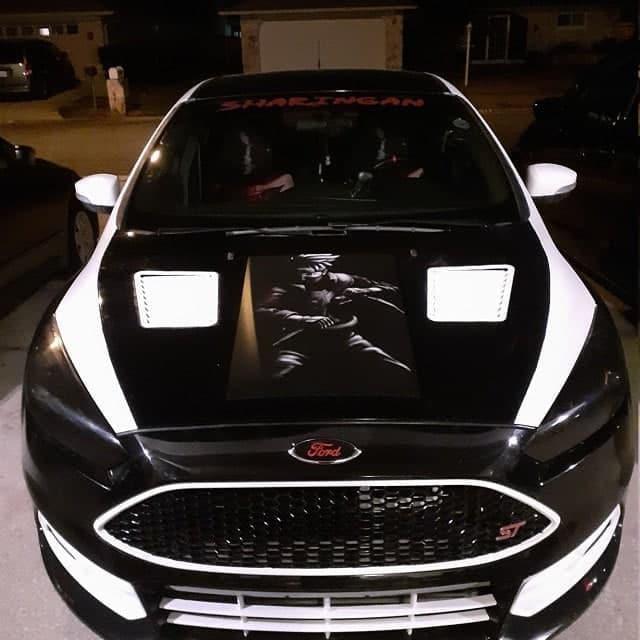 Custom black Ford with unique artwork on the hood and sporty design, parked at night.