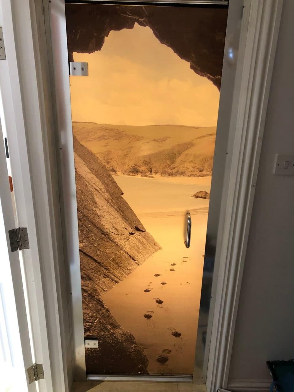 Custom door decal featuring a serene beach scene with footprints in the sand and rocky cliffs.