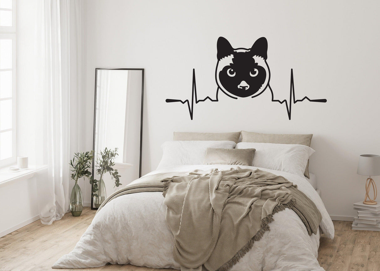 Siamese cat wall decal above a stylish bed, adding a playful touch to a cozy bedroom decor.