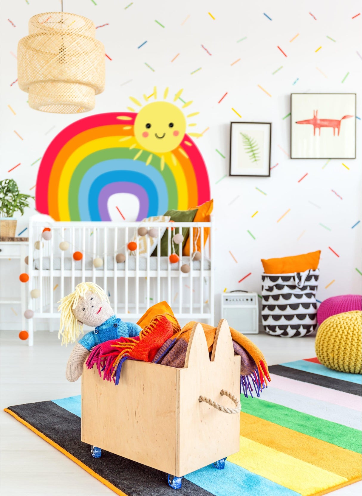 Colorful nursery with a rainbow wall sticker, playful decor, and toys in a wooden storage box.