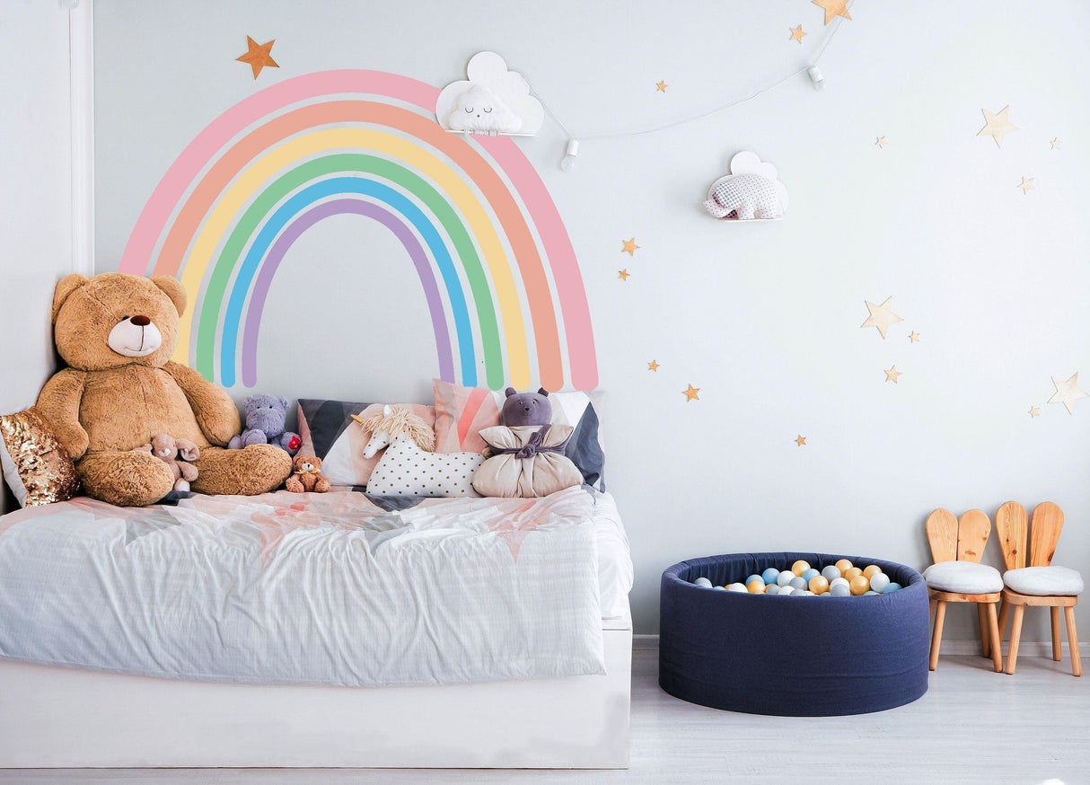 Pastel rainbow wall sticker in a cozy nursery with teddy bears and colorful decor elements.
