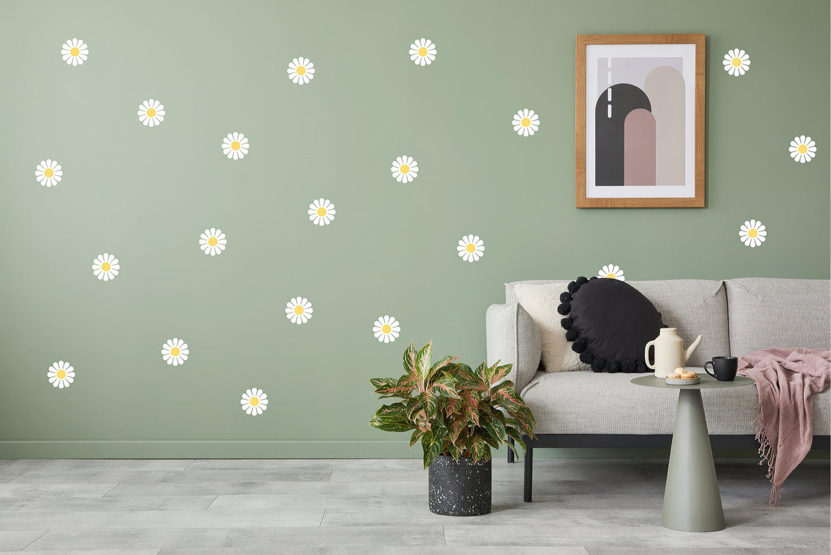 24 white daisy flower wall stickers on green wall in stylish living room with modern decor and plants.