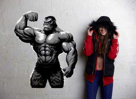Muscled gorilla wall decal alongside a woman in a hooded jacket, adding gym motivation to a workout space.