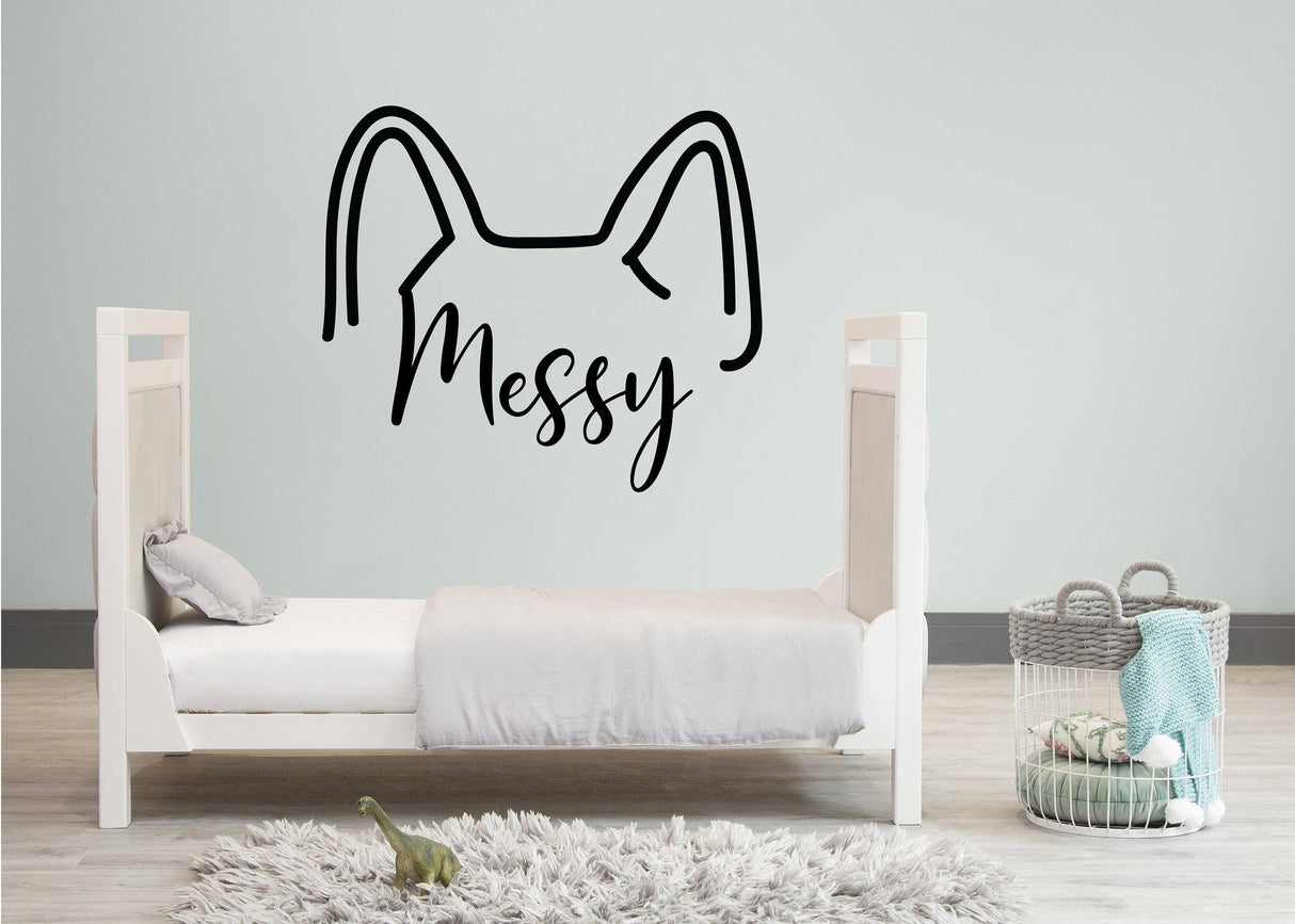 Custom cat ear wall decal with 'Messy' text above a minimalist child's bed in a cozy room.