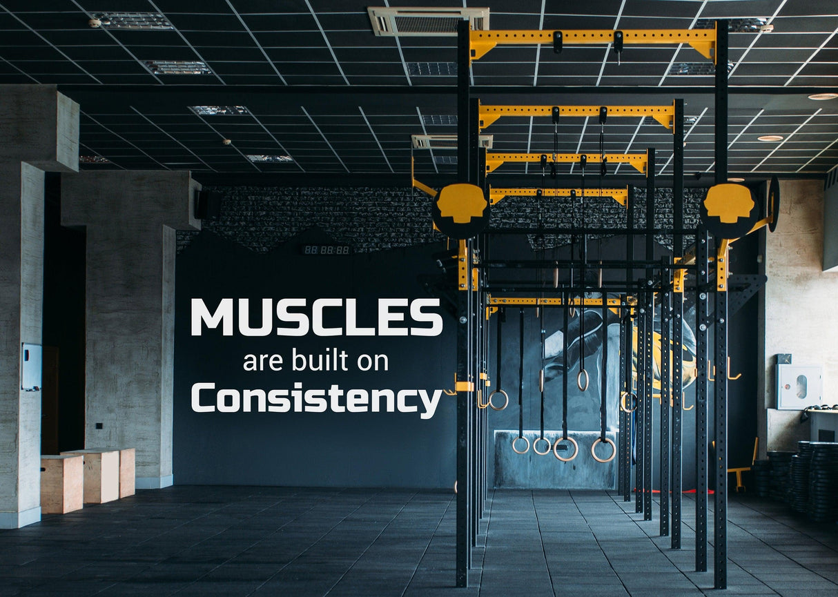 Gym interior with motivational quote 'Muscles are built on Consistency' on wall, inspiring fitness and training.