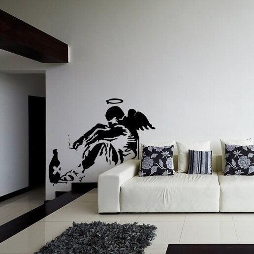 Banksy Fallen Angel wall decal on a modern living room wall, showcasing urban art decor.