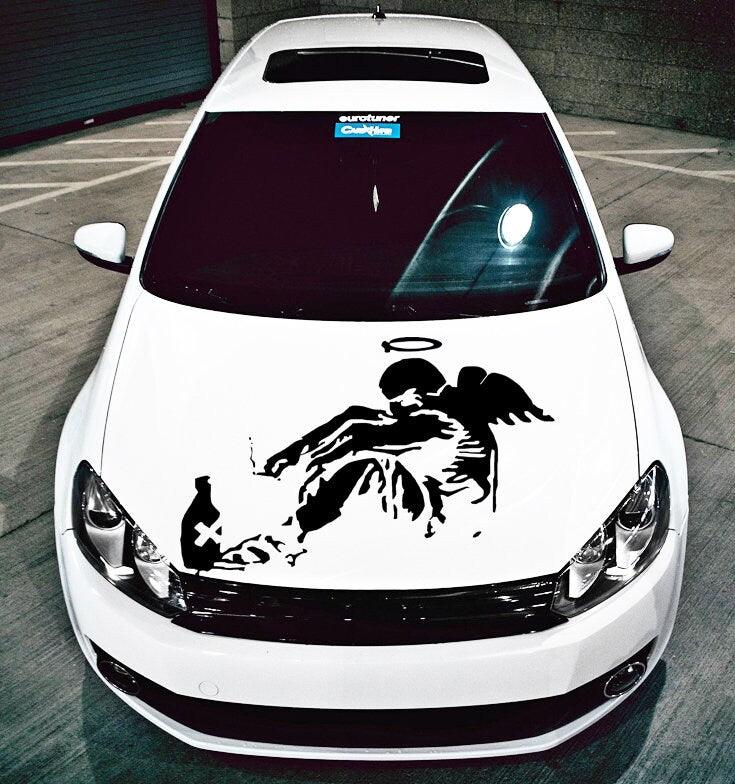 Banksy inspired Fallen Angel graffiti decal on a white car hood, featuring urban art and unique design.