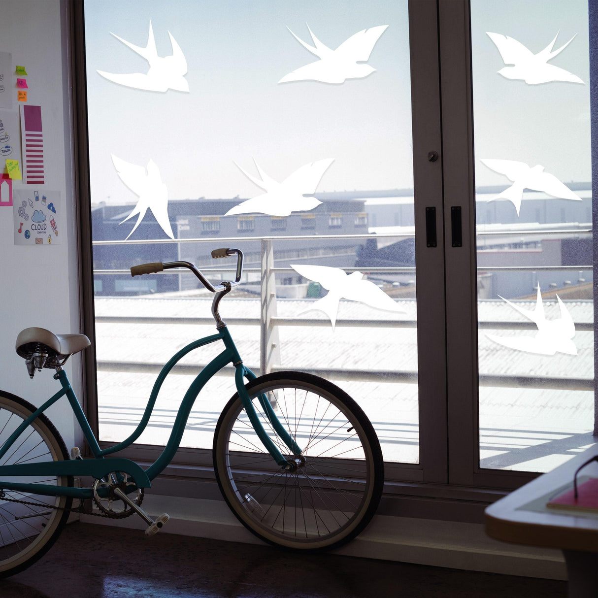 Anti-collision bird stickers on a glass door, enhancing safety and decor with a bicycle in the foreground.