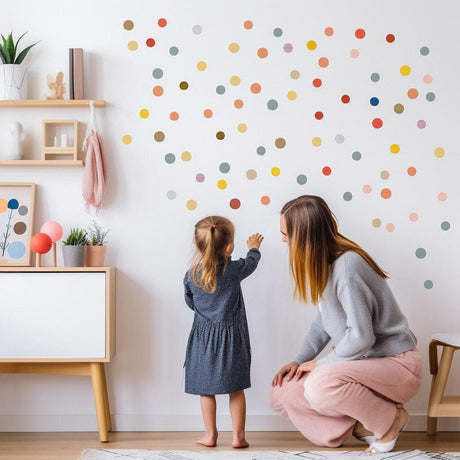 Child and parent interacting with vibrant watercolor dot wall decals in a cozy playroom.