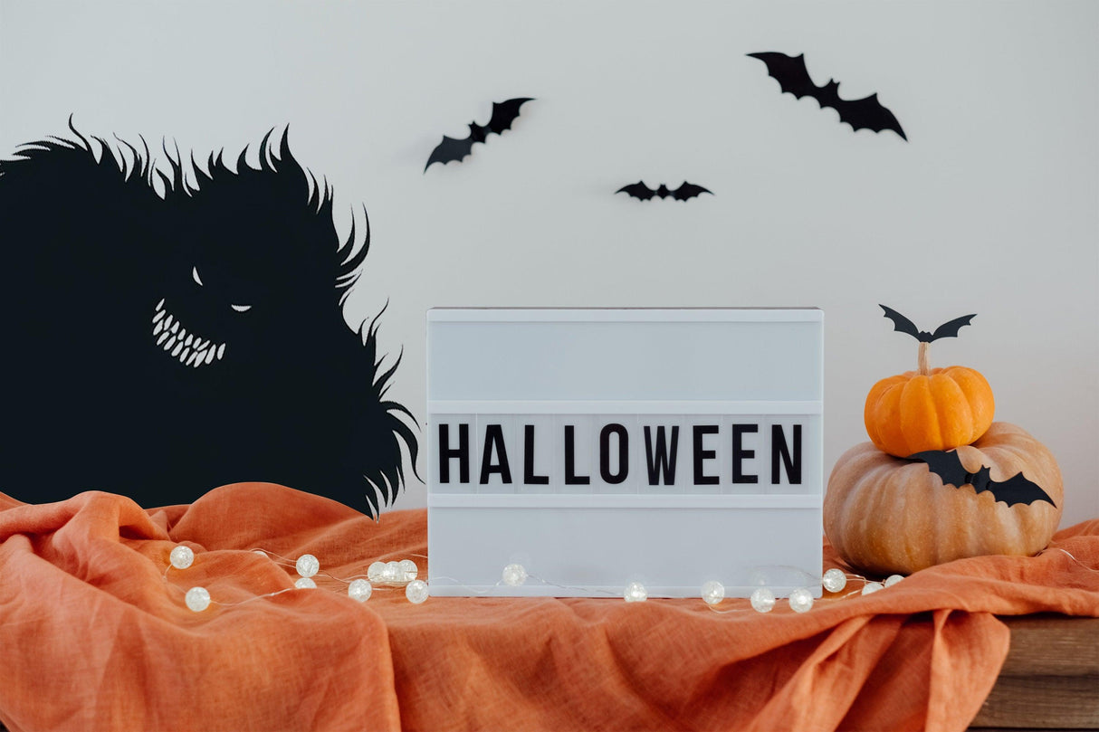 Halloween decor with spooky silhouettes, light box displaying "HALLOWEEN," pumpkin, and decorative bats.