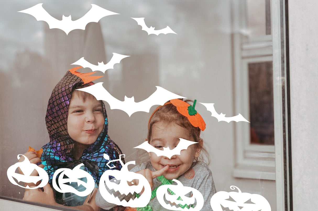 Kids enjoying Halloween window decals with festive pumpkins and bats decorations.