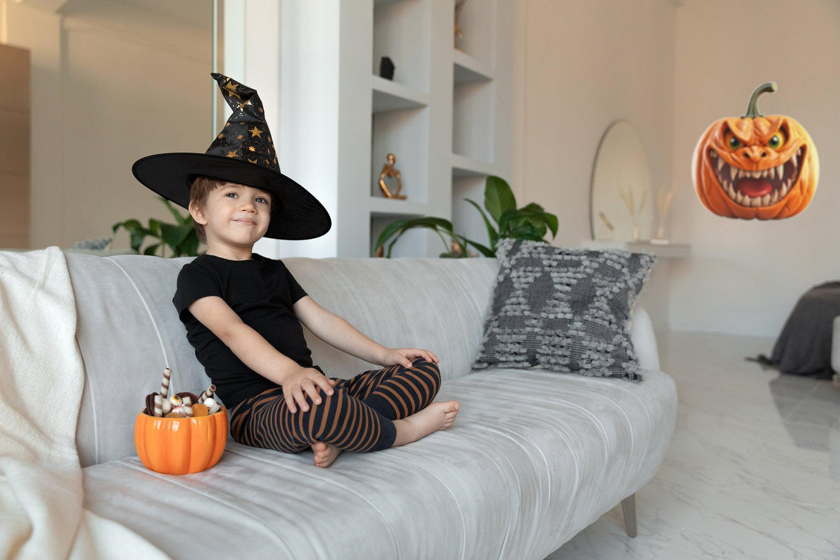 Child in a witch hat sitting on a couch with a pumpkin candy bowl and a spooky pumpkin decal nearby.