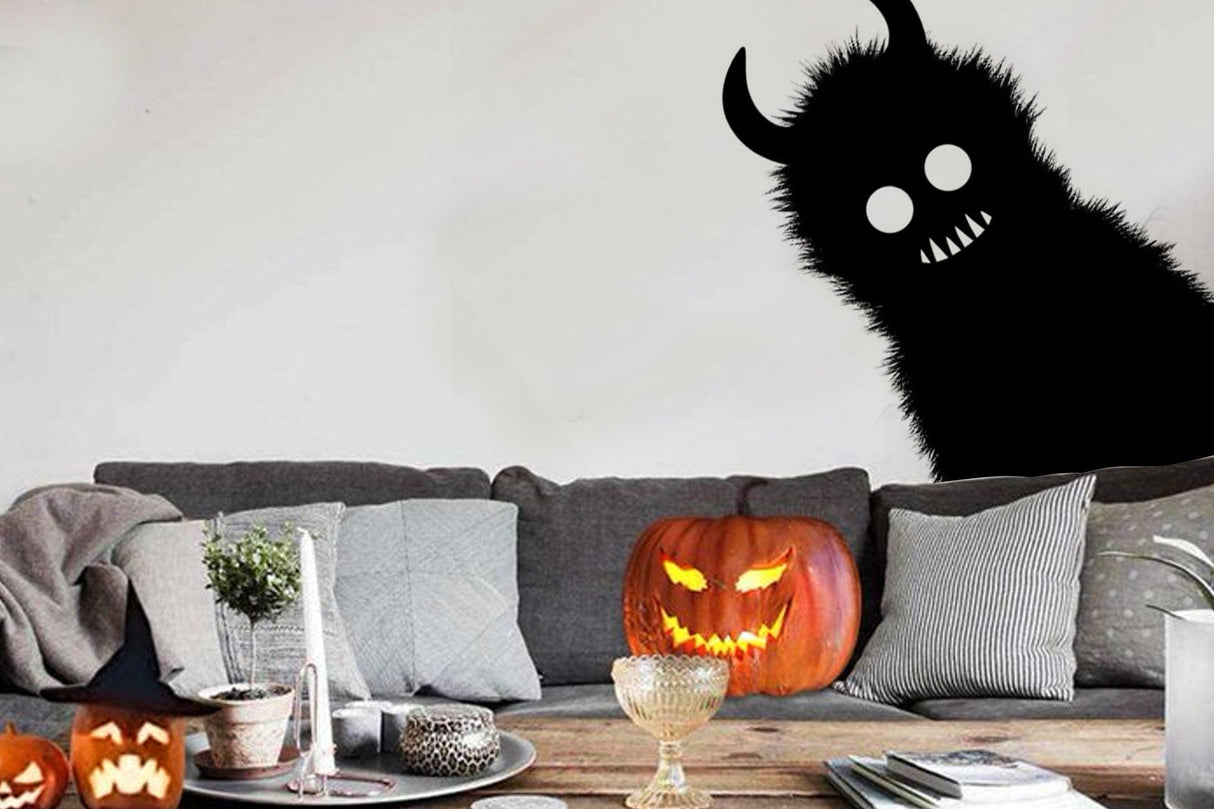 Spooky Halloween decor featuring a monster shadow sticker and carved pumpkins on a cozy couch.