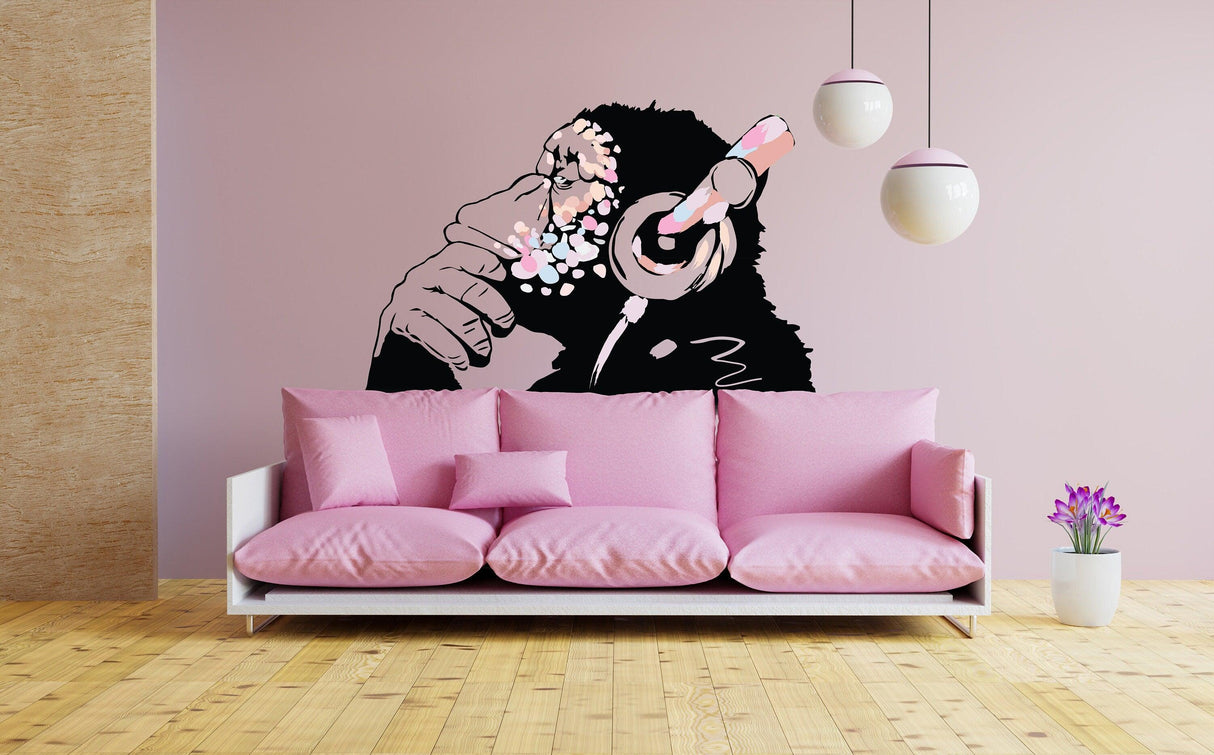Banksy-inspired pink monkey decal on wall above pink sofa in boho girls room decor.