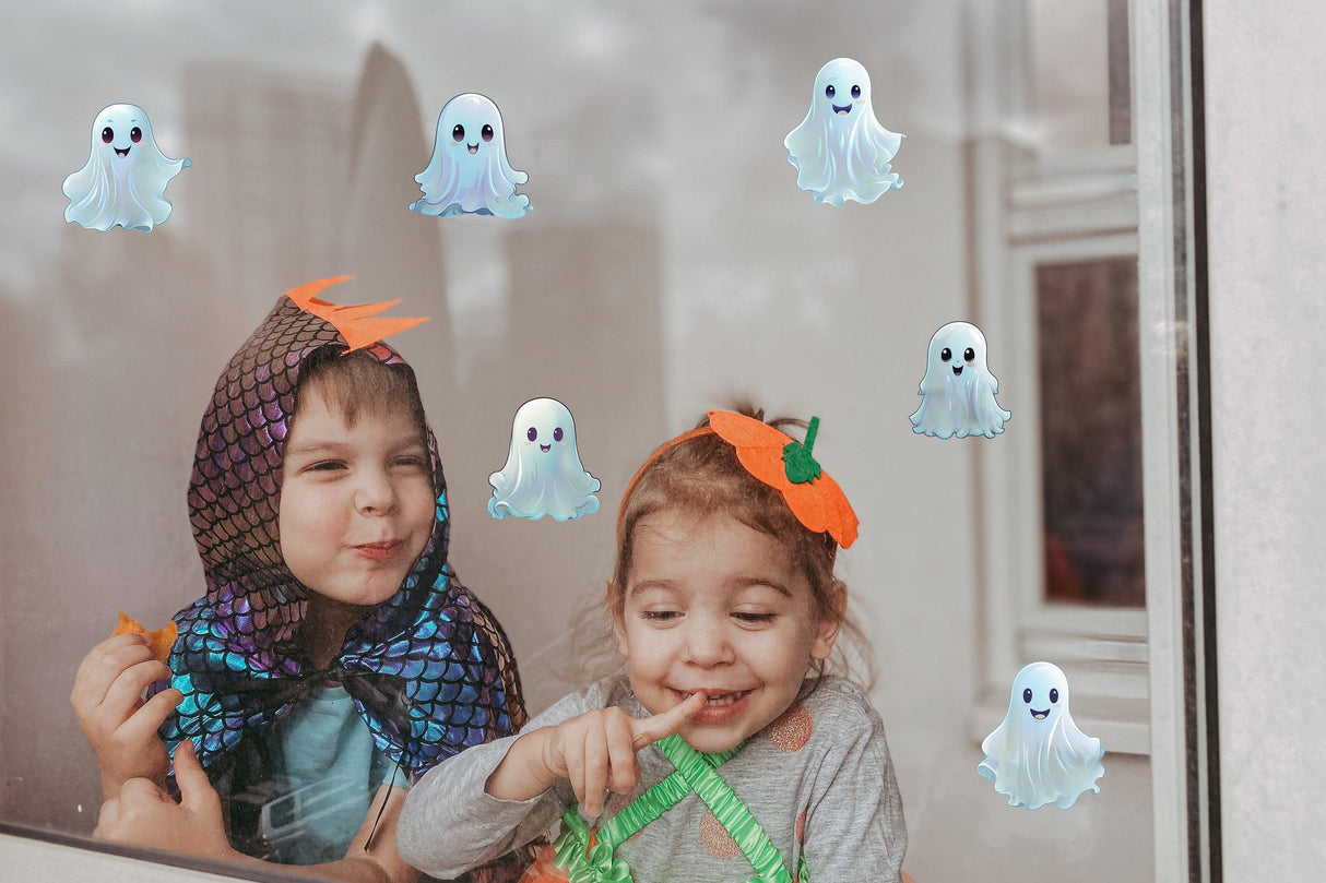 Kids in Halloween costumes playing with spooky white ghost window decals on a glass window.