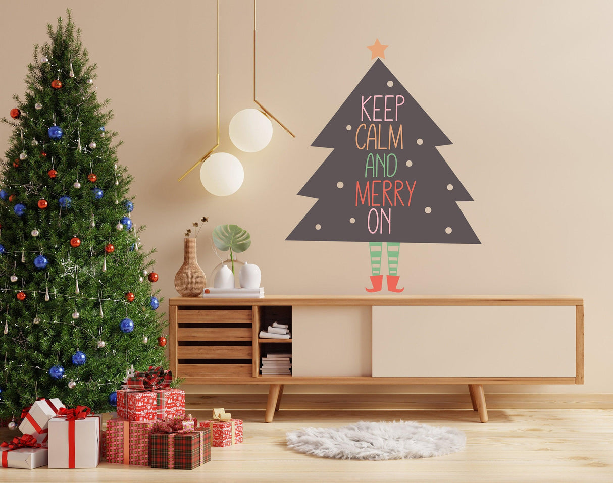 Whimsical Christmas tree wall vinyl sticker with legs and "Keep Calm and Merry On" text in colorful decor.