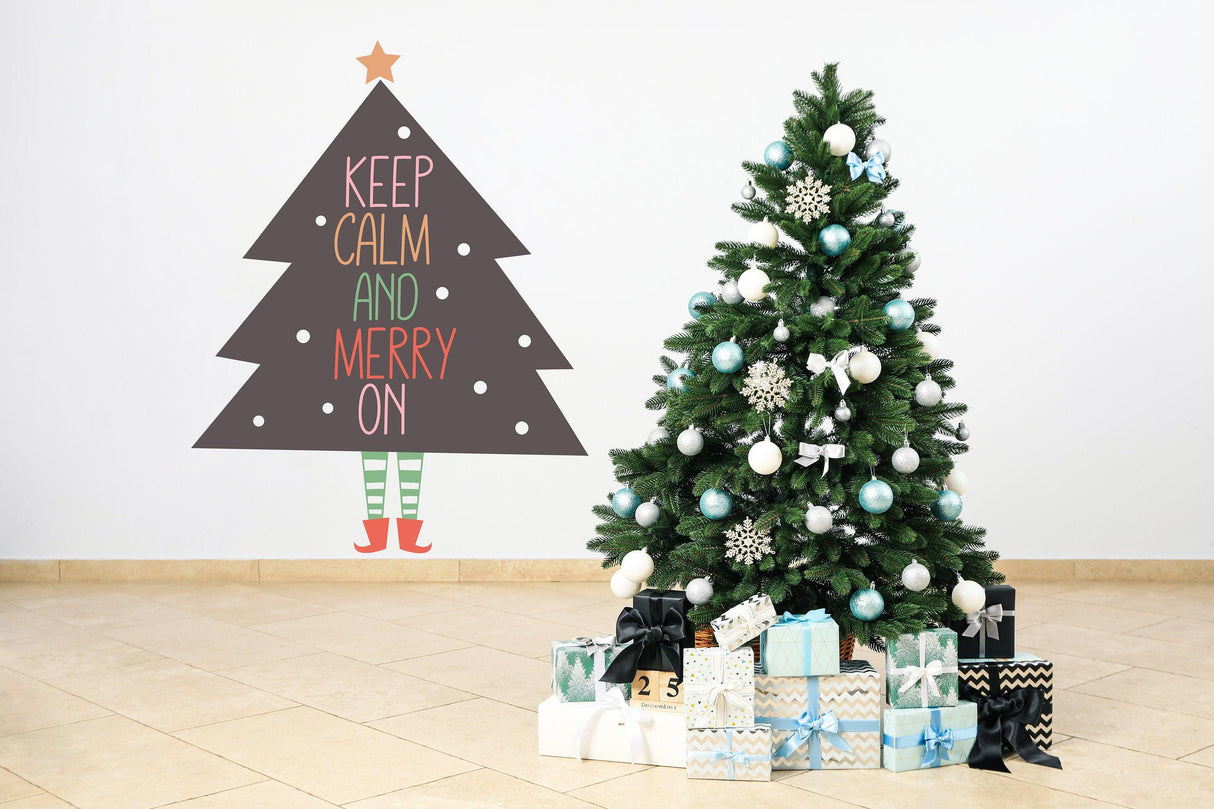 Whimsical Christmas tree wall sticker with legs saying 'Keep Calm and Merry On' beside a beautifully decorated tree.