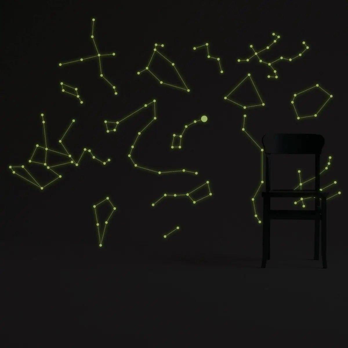 Glowing starry sky ceiling decals in green on a dark wall, featuring luminous constellation stickers with a chair.