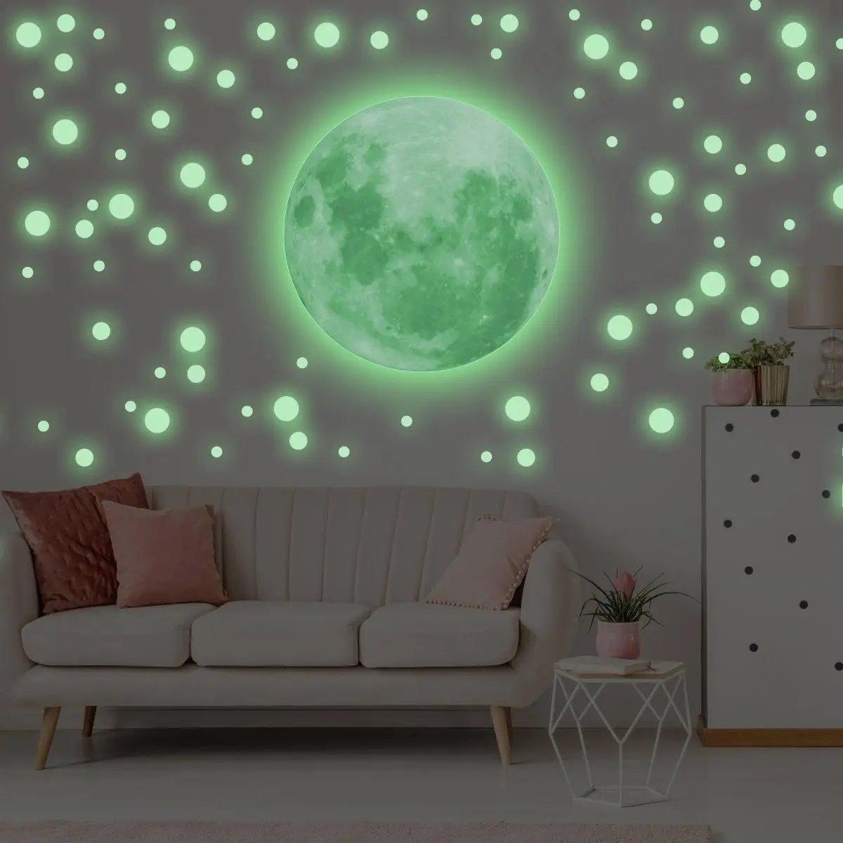 Luminous wall decal set featuring a glowing green moon and round star stickers in a cozy living room.