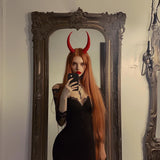 Model wearing red 3D printed demon horns in gothic outfit, posing in front of a mirror.