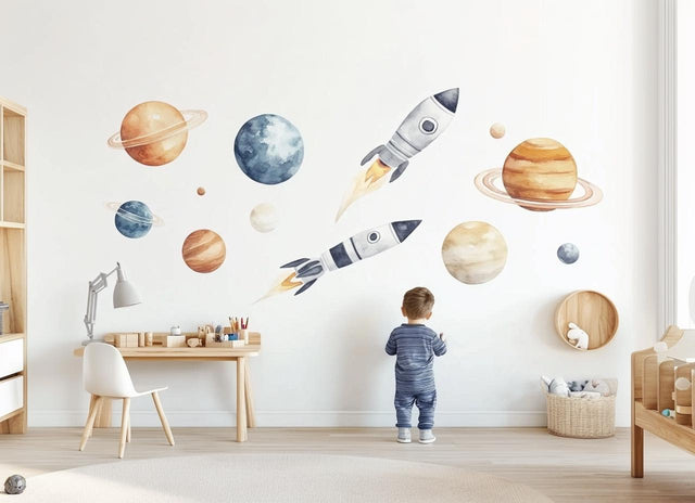 A child’s bedroom wall decorated with large watercolor rocket ships and planets in warm orange, beige, and dusty blue tones, creating a soft and playful outer space theme.