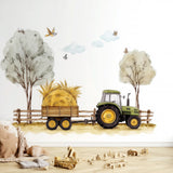 A farm-themed nursery wall decal showing a green tractor pulling a hay-loaded wooden trailer along a dirt path, with trees, birds, clouds, and a wooden fence in a soft watercolor style above a scattered toy scene on a wood floor.
