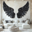 Large black angel wings wall decal applied to a living room wall above a white sectional couch, with detailed feather textures and a gothic-modern aesthetic.