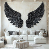 Large black angel wings wall decal applied to a living room wall above a white sectional couch, with detailed feather textures and a gothic-modern aesthetic.