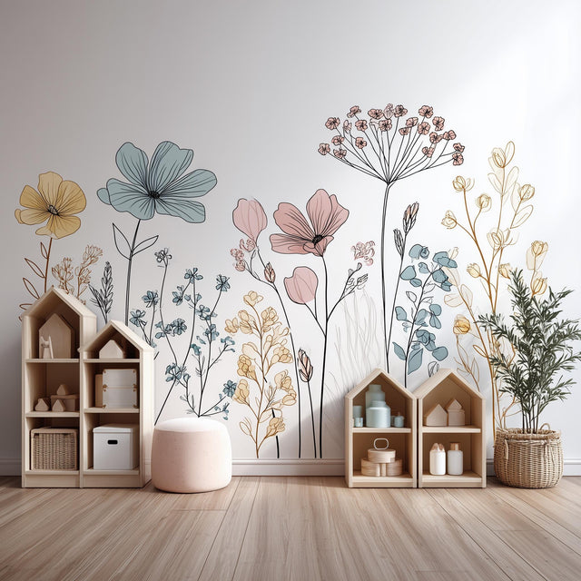 A stylish children's room with pastel-colored floral line art wall decals behind toy shelves. The design features tall hand-drawn flowers in soft pink, blue, yellow, and tan tones, adding a calming, boho feel to the space.