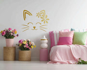 Wall decal of a simple cat face with closed eyes, whiskers, and a floral design on one ear.