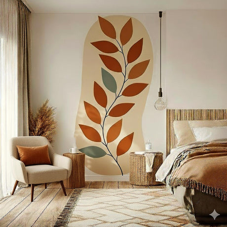 Large abstract wall decal featuring a vertical botanical branch with terracotta and green leaves on a beige organic background. Applied to a bedroom wall near a bed and armchair in a natural, warm-toned interior.
