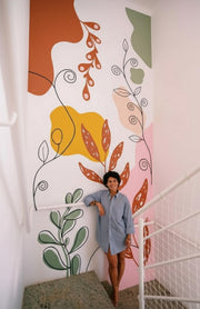 Large abstract botanical wall decal with colorful shapes and flowing lines applied to a staircase wall.
