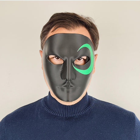 Person wearing a black 3D-printed half-face mask with a green crescent design around one eye; photographed from various angles including front, side, and ¾ view, showing detail, shape, and fit of the mask.