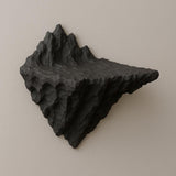 A 3D printed black wall shelf designed to resemble a jagged mountain peak or volcanic rock formation, mounted on a beige wall above a wooden surface.