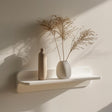 Minimalist 3D printed wall shelf in matte white, holding decorative vases and dried plants, mounted on a softly lit modern wall