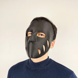 Person wearing a matte black 3D printed face mask with organic cutouts and a sleek, form-fitting shape, secured with adjustable elastic straps.