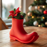3D printed vase shaped like a Christmas boot, made of matte PLA plastic, displayed on a wooden table with festive holiday decorations in background