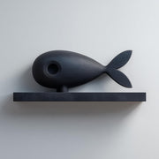 3D printed matte PLA wall shelf with a stylized fish figure resting on a slim rectangular ledge.
