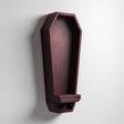 3D printed vertical coffin-shaped wall shelf in dark matte PLA with a small ledge at the bottom, mounted on a light-colored wall.