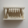 3D printed matte PLA wall shelf shaped like a wide monster jaw with upper and lower fangs forming a small display nook in the mouth.