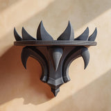 3D printed dark fantasy wall shelf with curved spikes like a black crown, mounted on a warm beige wall in natural light.