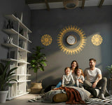 A horizontal arrangement of three golden-yellow designs on a light background. The center features a large, sharp-edged sunburst or sun symbol, with two smaller, intricate floral mandalas on either side.