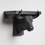 3D printed bull head wall shelf with long curved horns supporting a flat floating ledge, mounted on a clean minimalist wall.