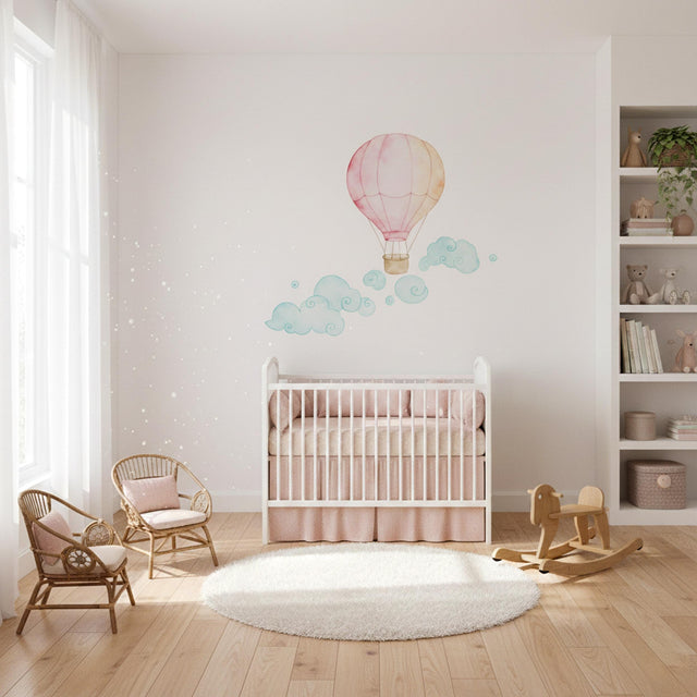 A soft watercolor illustration of a pink and pale orange hot air balloon floating above several whimsical, swirling teal and light green clouds on a plain white background.