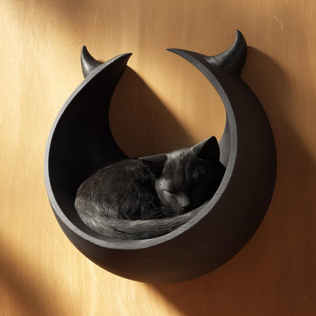 3D printed dark fantasy crescent moon wall mounted cat bed in matte black PLA with a sleeping grey cat inside, warm wooden background.
