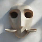 3D printed minimalist face wall shelf with two removable cup platforms on each side, mounted on a textured neutral interior wall.