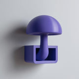 3D printed mushroom wall shelf with a domed cap and stem flowing into a small rectangular cubby tray, visible print texture, mounted on a clean wall.